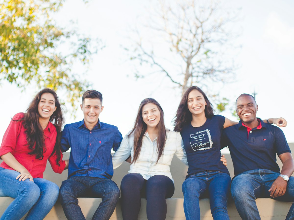 A smiling group of college students sits together outdoors.