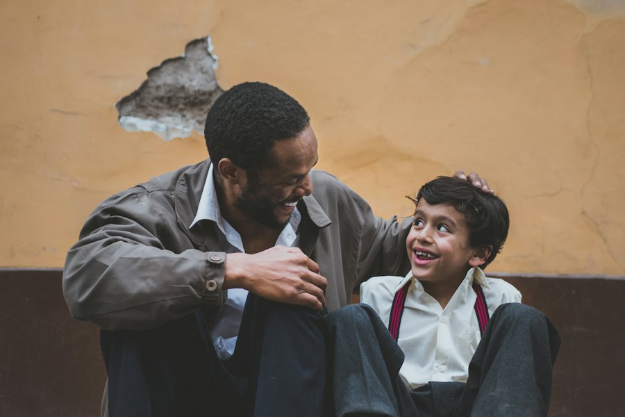 A father and his young son sit together, smiling and talking.