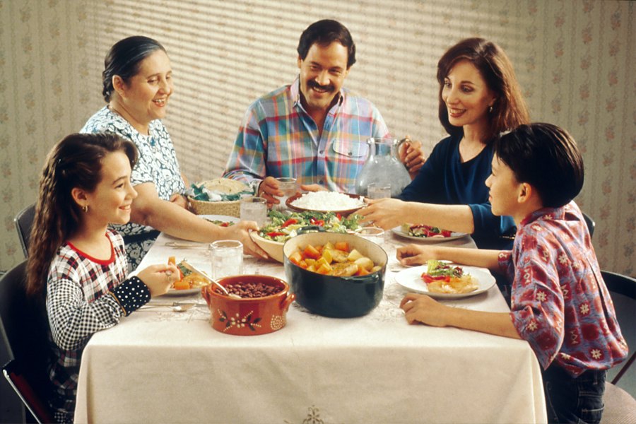 A multigenerational family shares a meal around the dinner table.